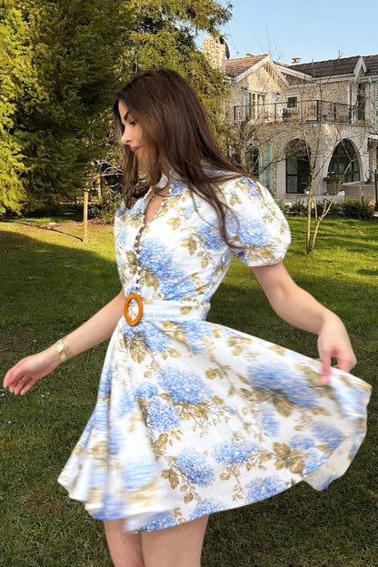 Woman in a floral dress standing outdoors with a building in the background