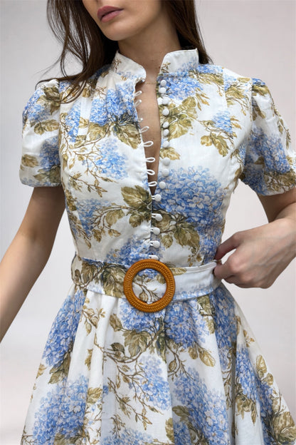 Woman wearing a floral dress with a wooden belt buckle on a plain background