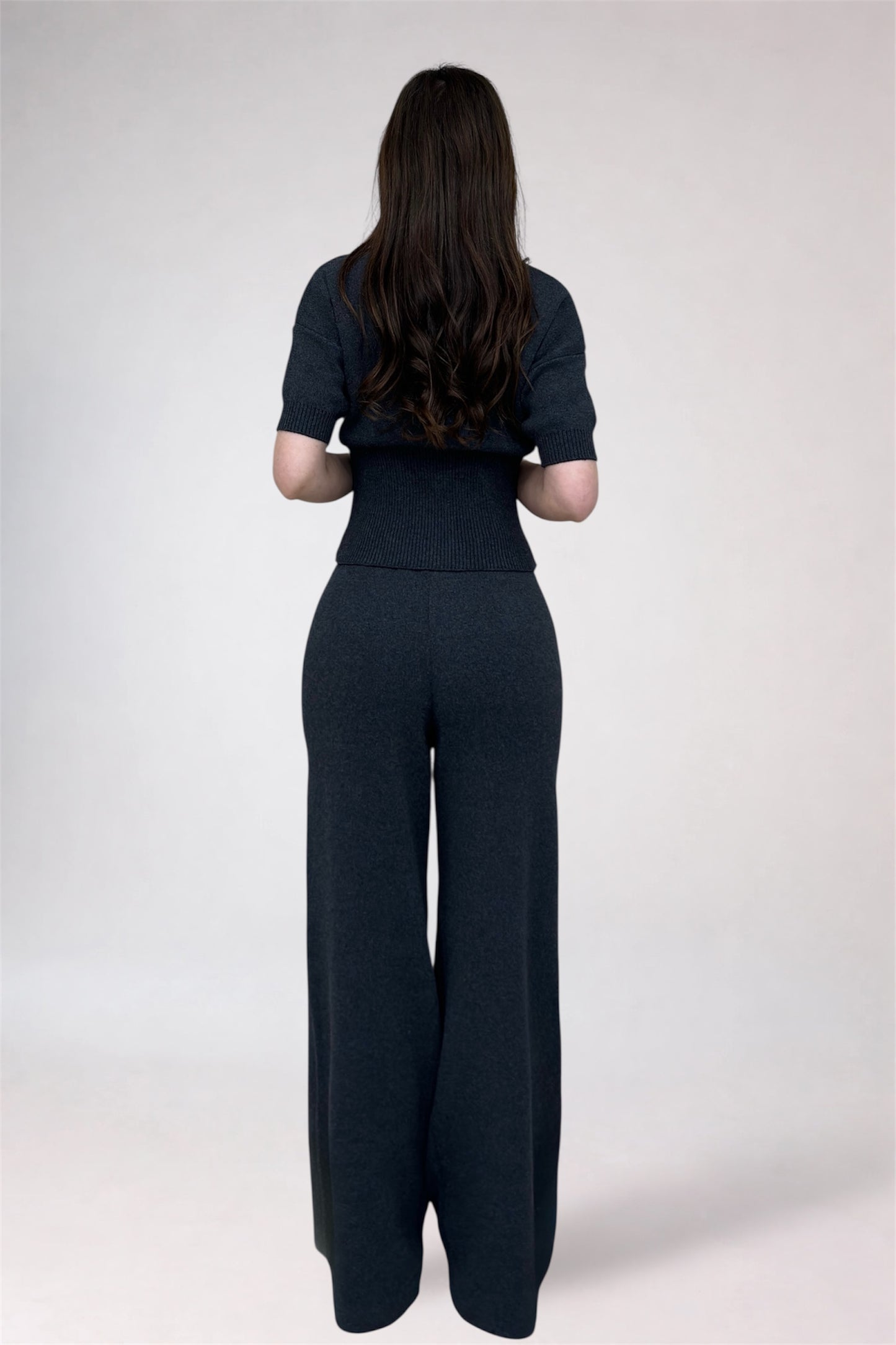 Person wearing a black outfit with wide-leg pants on a white background
