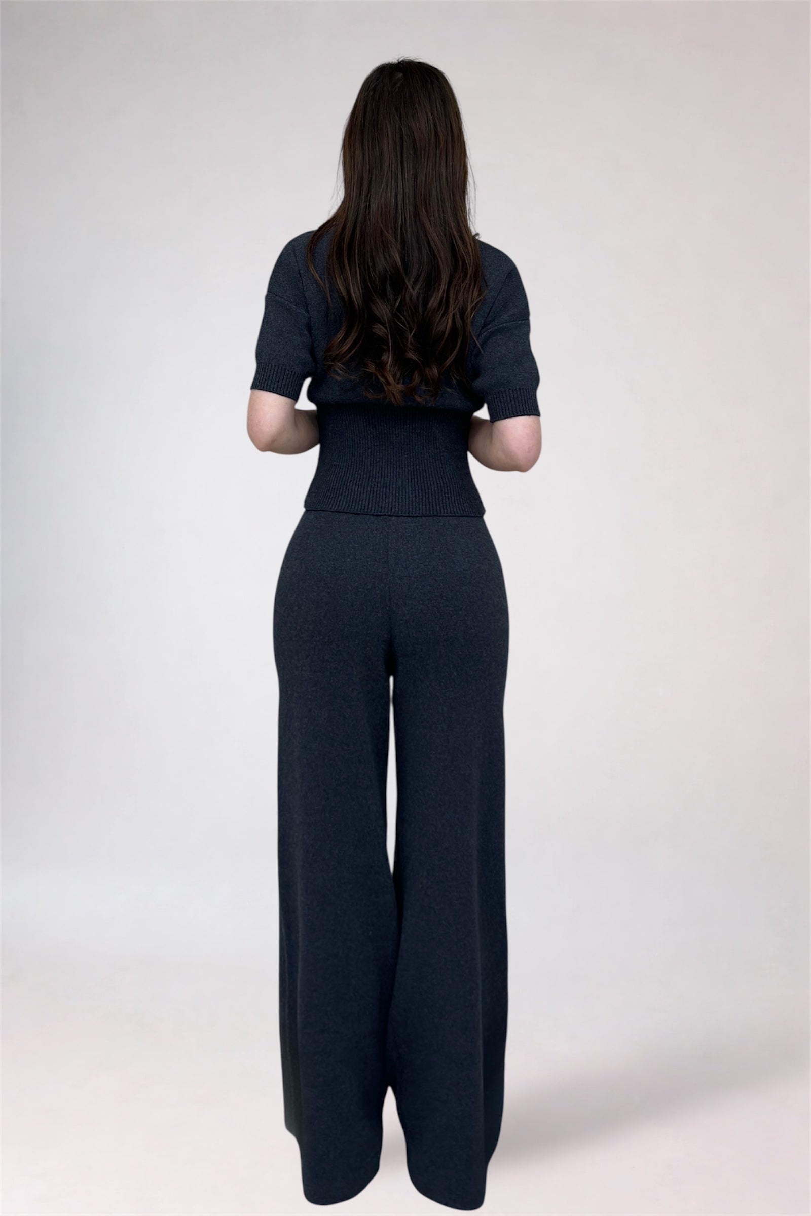 Person wearing a black outfit with wide-leg pants on a white background