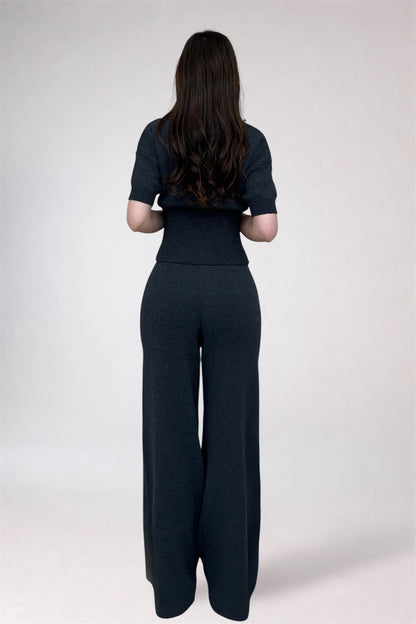 Person wearing a black outfit with wide-leg pants on a white background