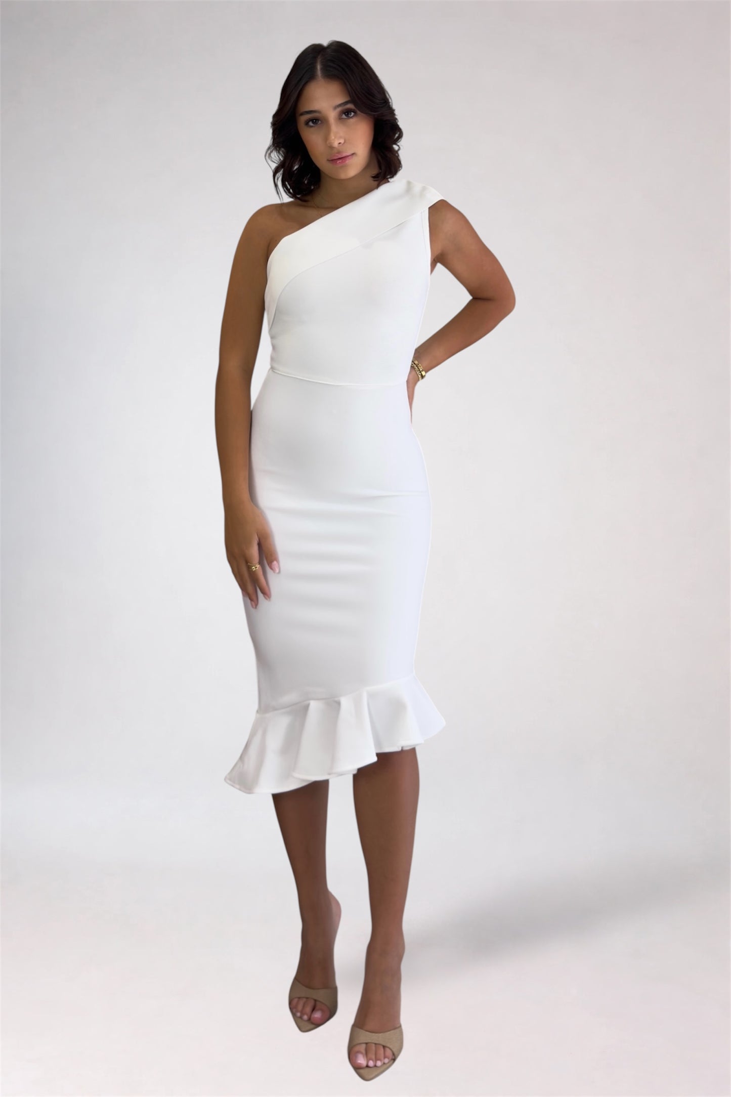 Woman wearing a white one-shoulder dress with ruffle details on a white background