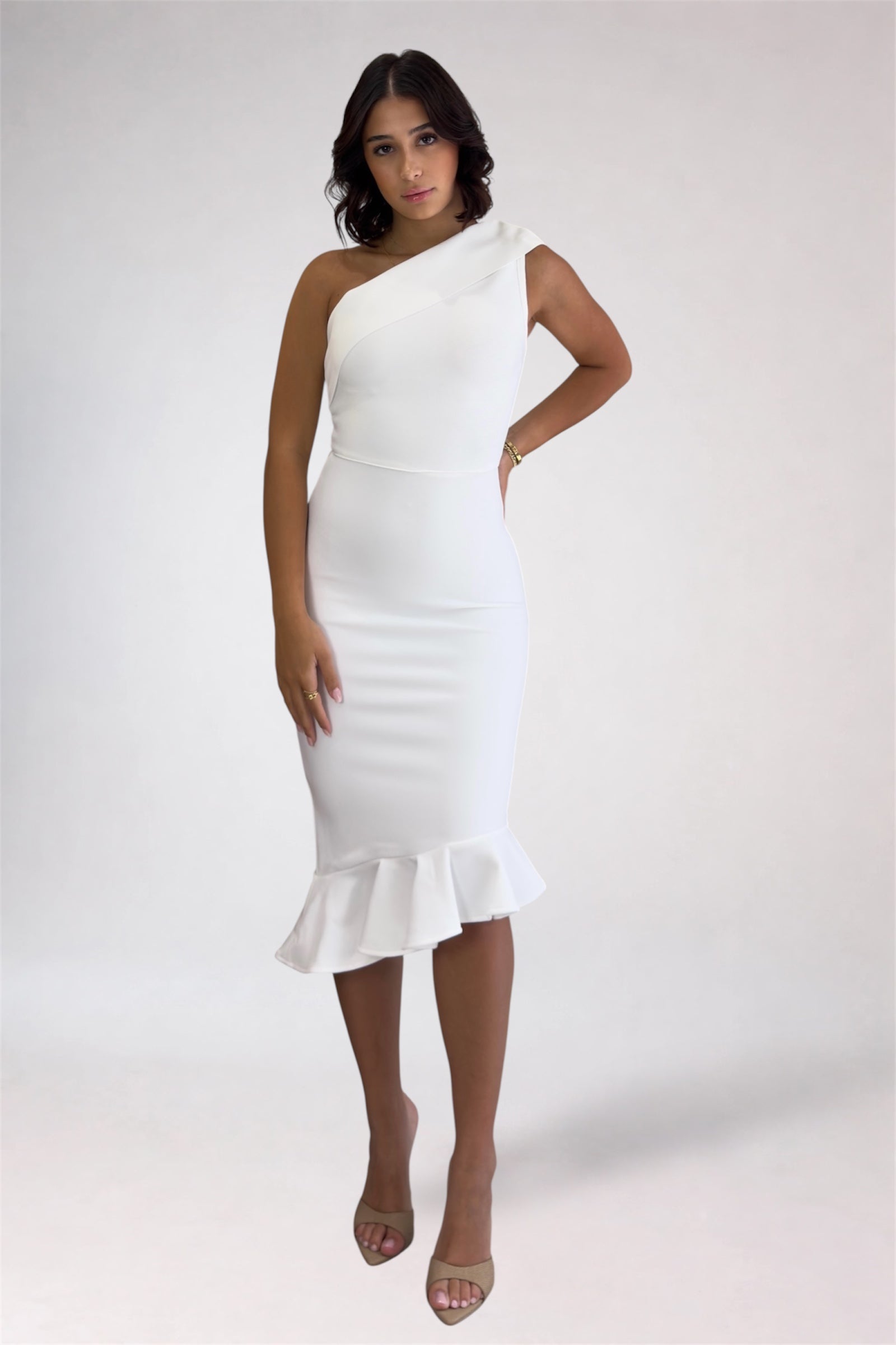 Woman wearing a white one-shoulder dress with ruffle details on a white background