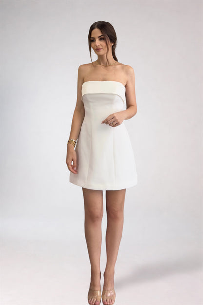 Woman wearing a white strapless dress on a plain background