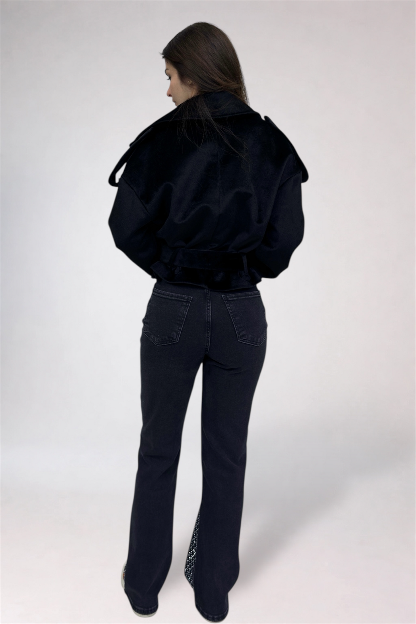 Person wearing a black jacket and jeans on a white background