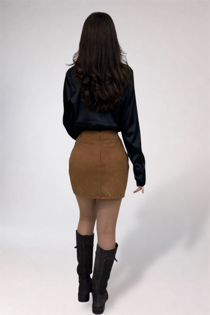 Person wearing a black blouse, brown skirt, and black boots on a white background