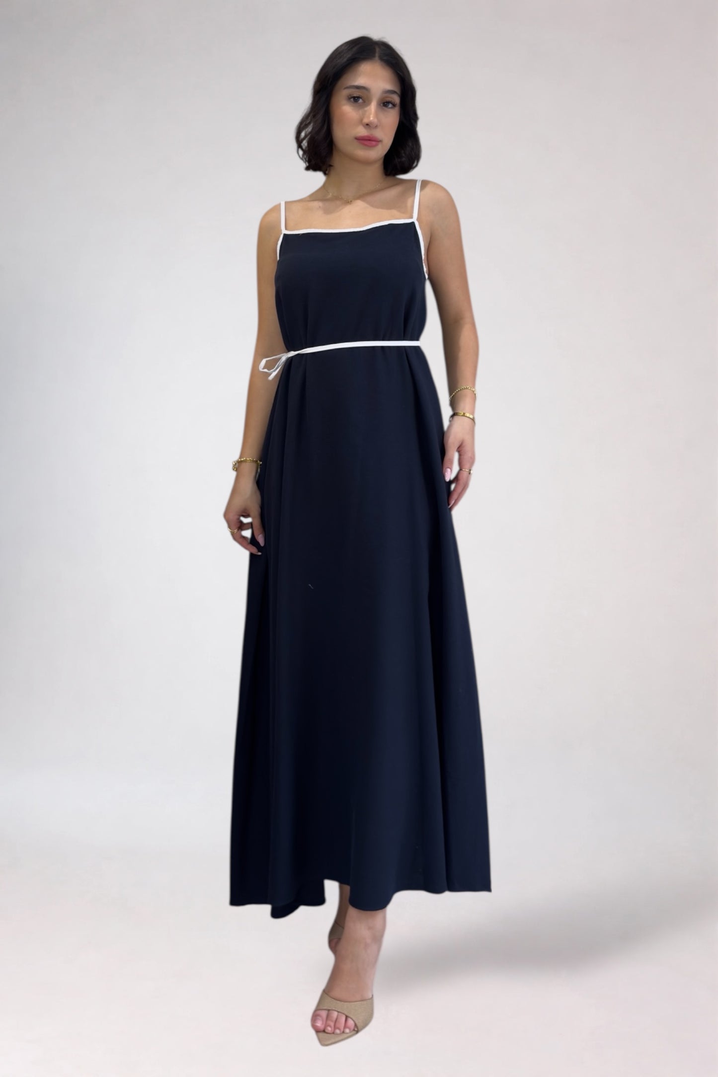 Woman wearing a navy blue dress with thin straps on a white background