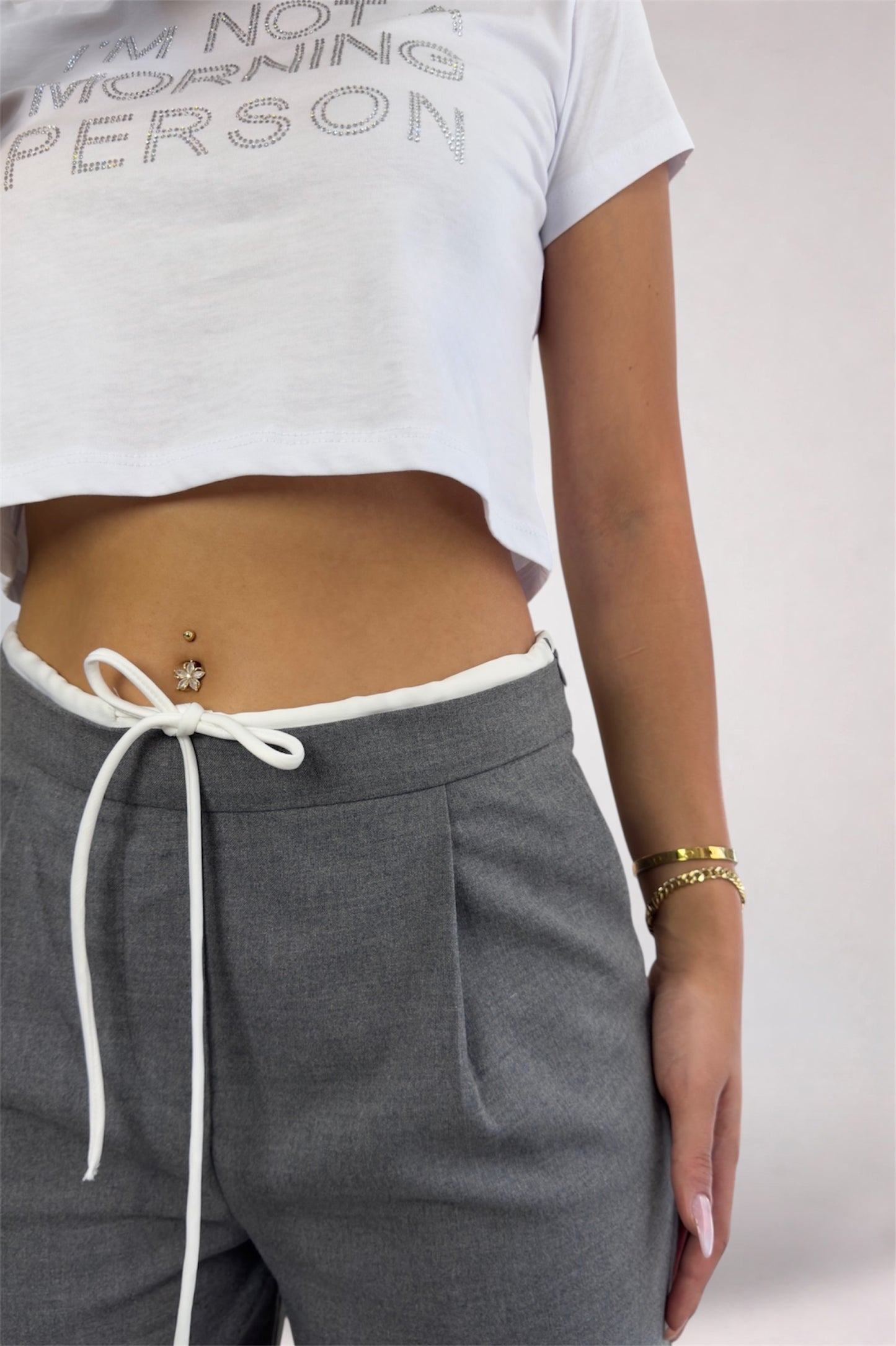Person wearing a white t-shirt with text and gray sweatpants on a plain background