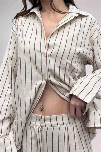 Person wearing a white and brown striped shirt and pants with a plain background