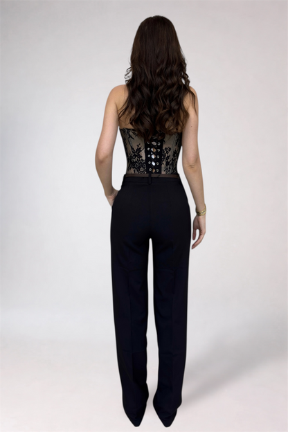 Woman wearing a black jumpsuit with lace detailing on a white background