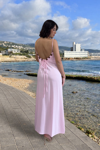 Woman in a pink dress standing by the sea with a scenic background