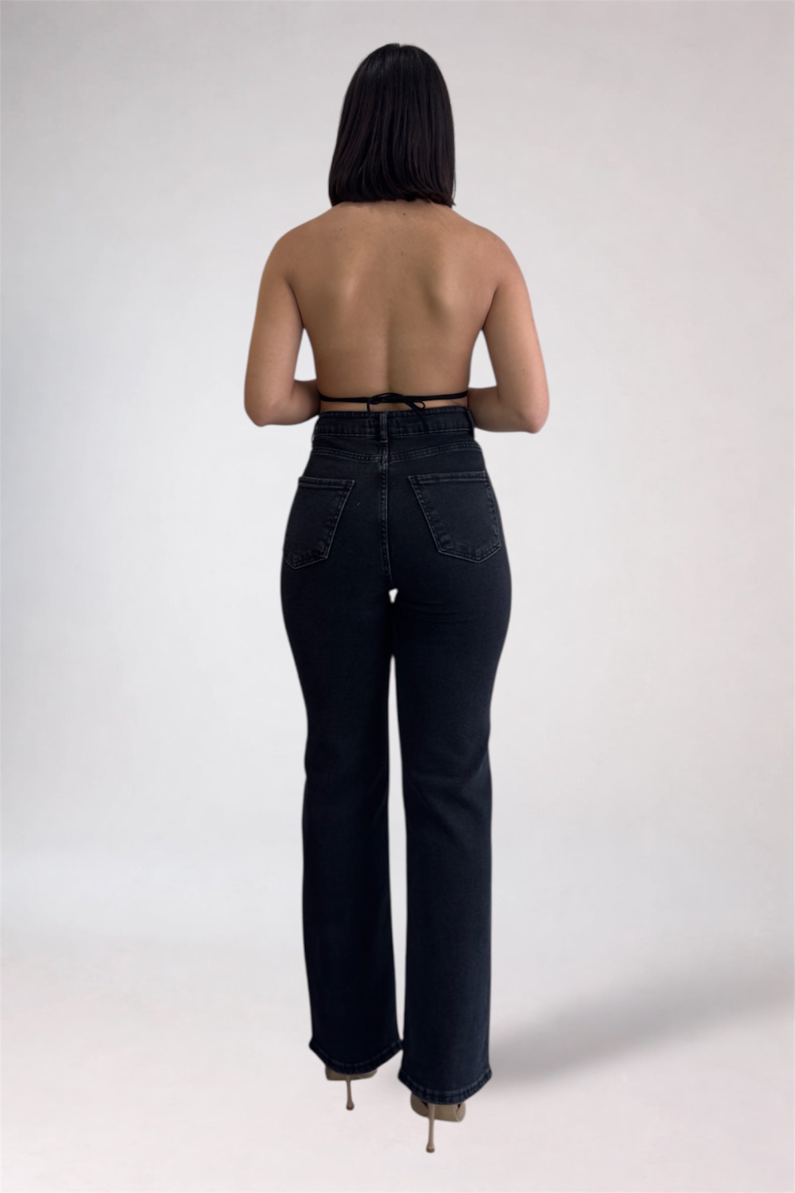 Person wearing black high-waisted jeans on a white background