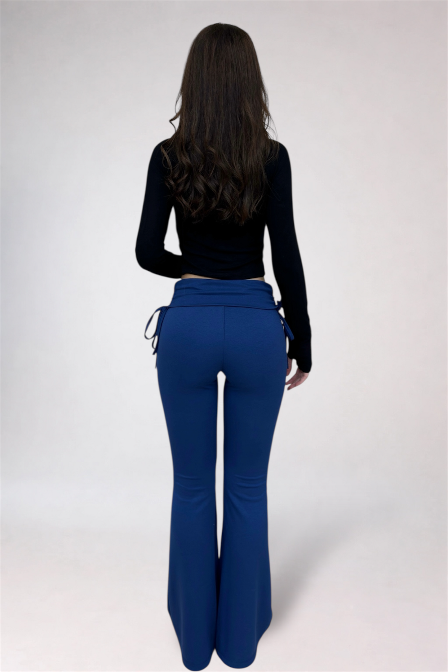 Person wearing a black top and blue pants on a white background