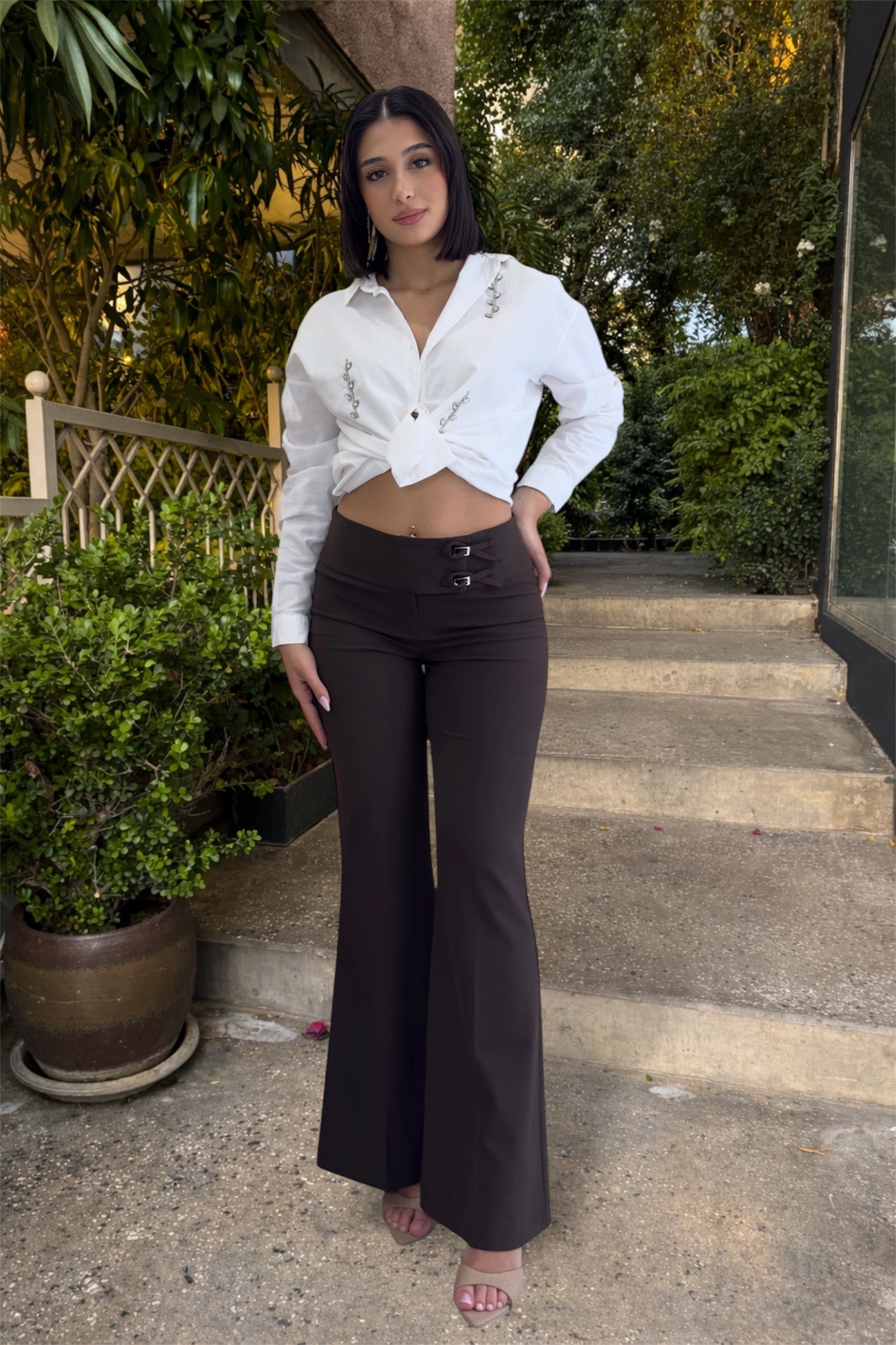 Woman in white blouse and dark pants standing on steps outdoors