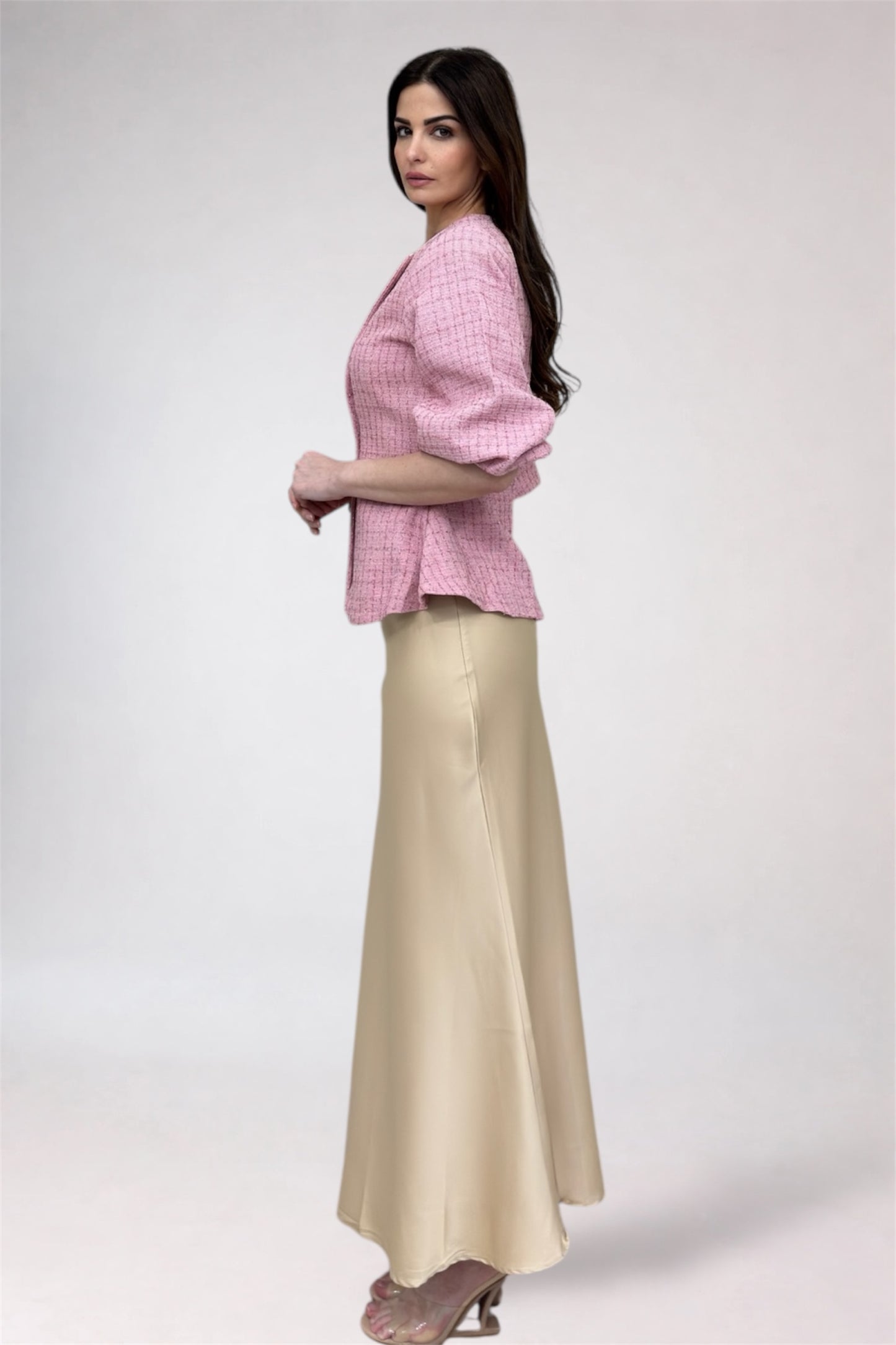 Woman wearing a pink checkered top and beige skirt on a white background