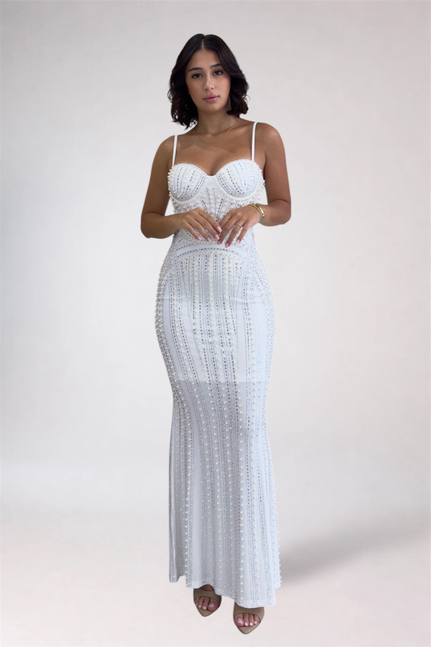 Woman wearing a white lace dress against a plain background