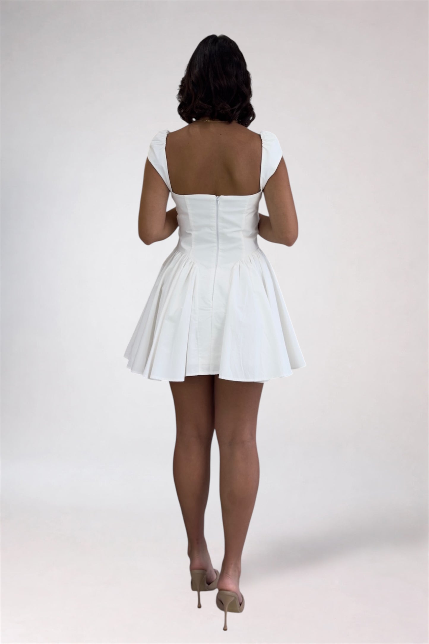 Person wearing a white dress on a plain background