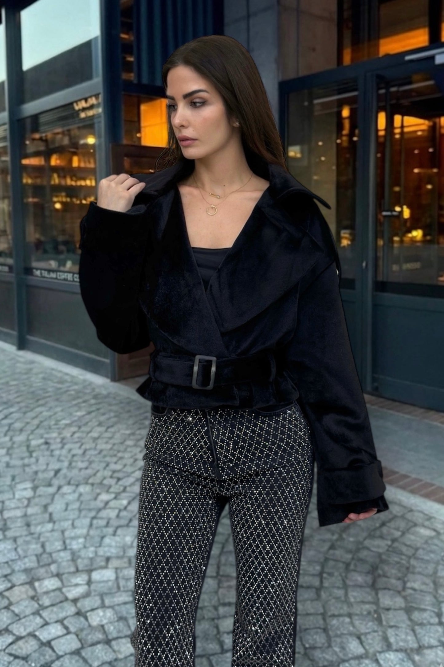 Woman in black outfit standing on a street with buildings in the background