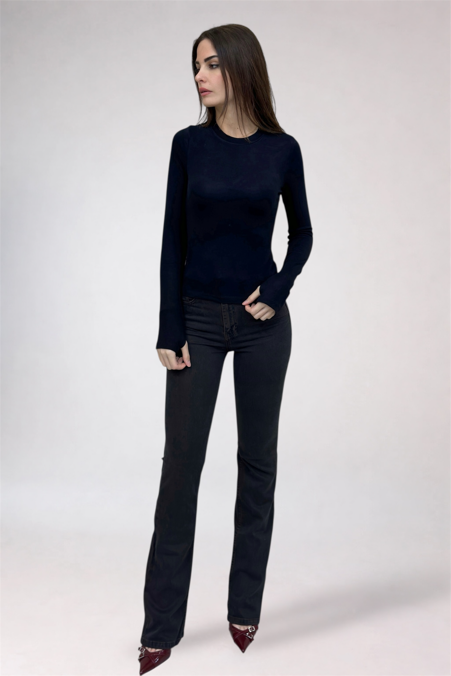 Woman wearing a black long-sleeve top and black jeans on a white background