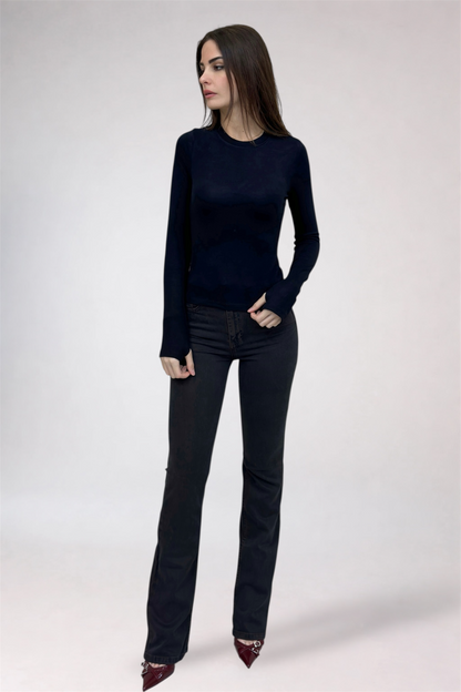 Woman wearing a black long-sleeve top and black jeans on a white background