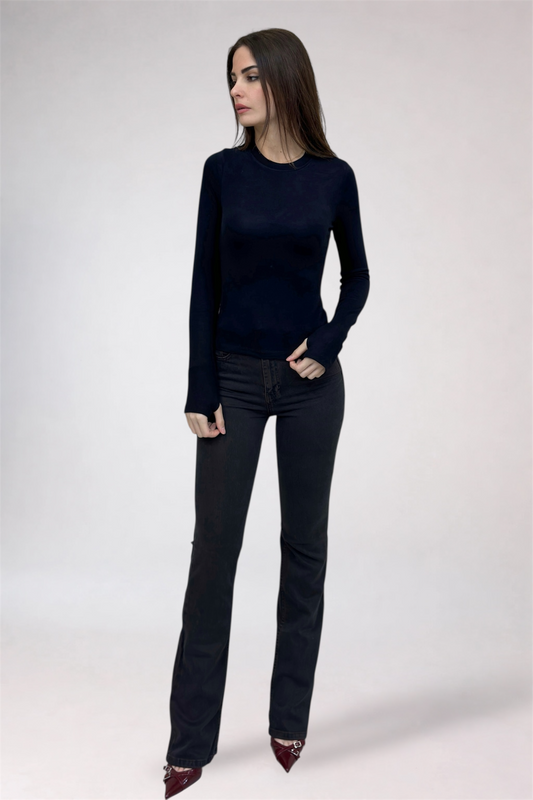 Woman wearing a black long-sleeve top and black jeans on a white background
