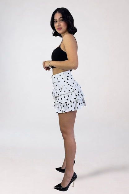 Woman wearing a black top and white polka dot skirt on a white background