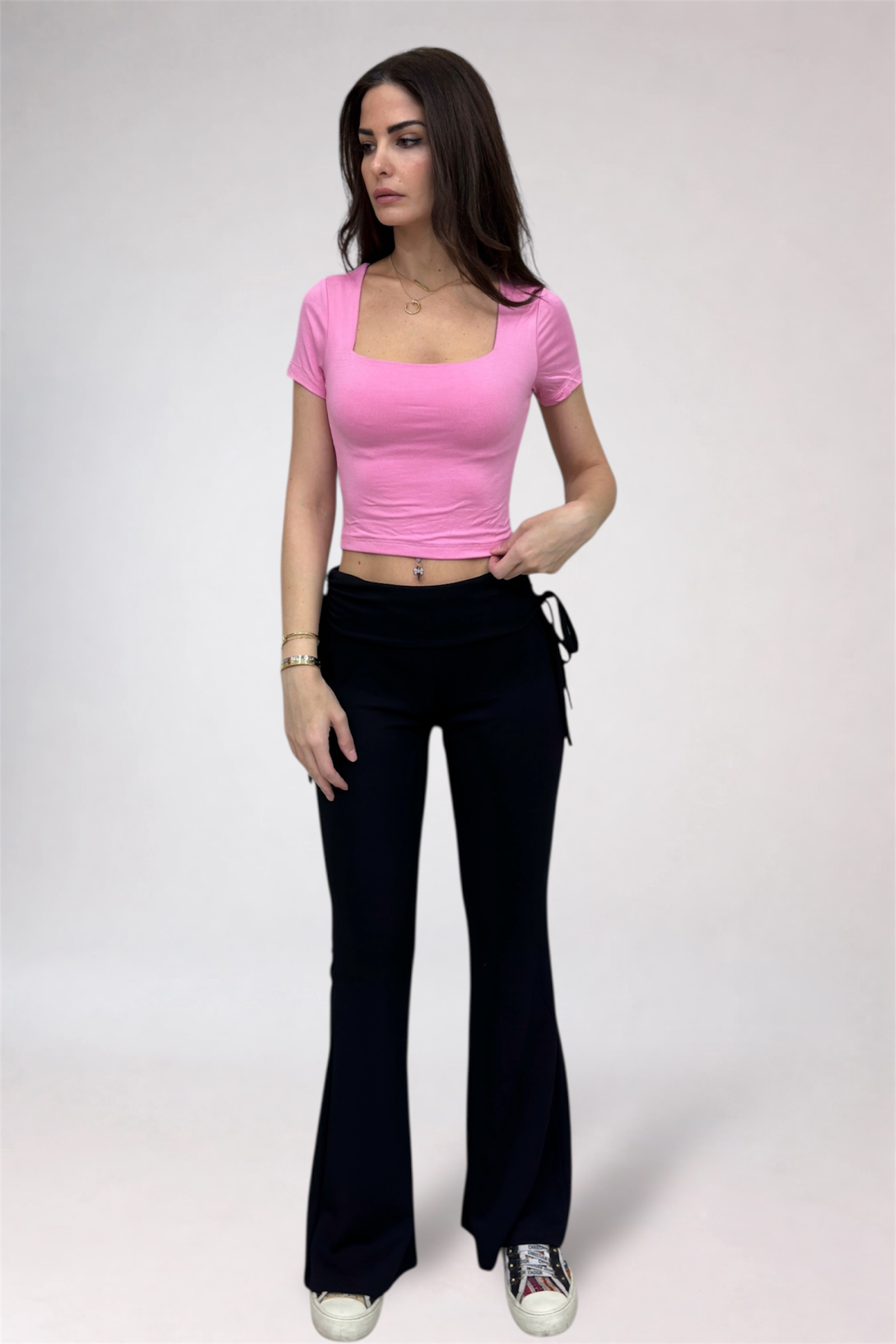 Woman wearing a pink top and black pants on a white background