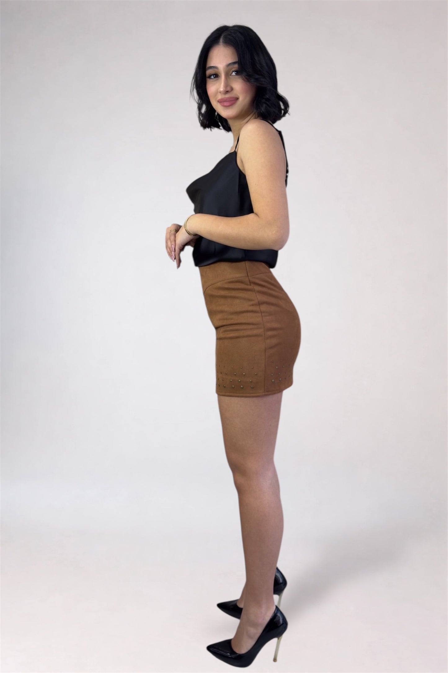 Woman wearing a black top and brown skirt on a white background