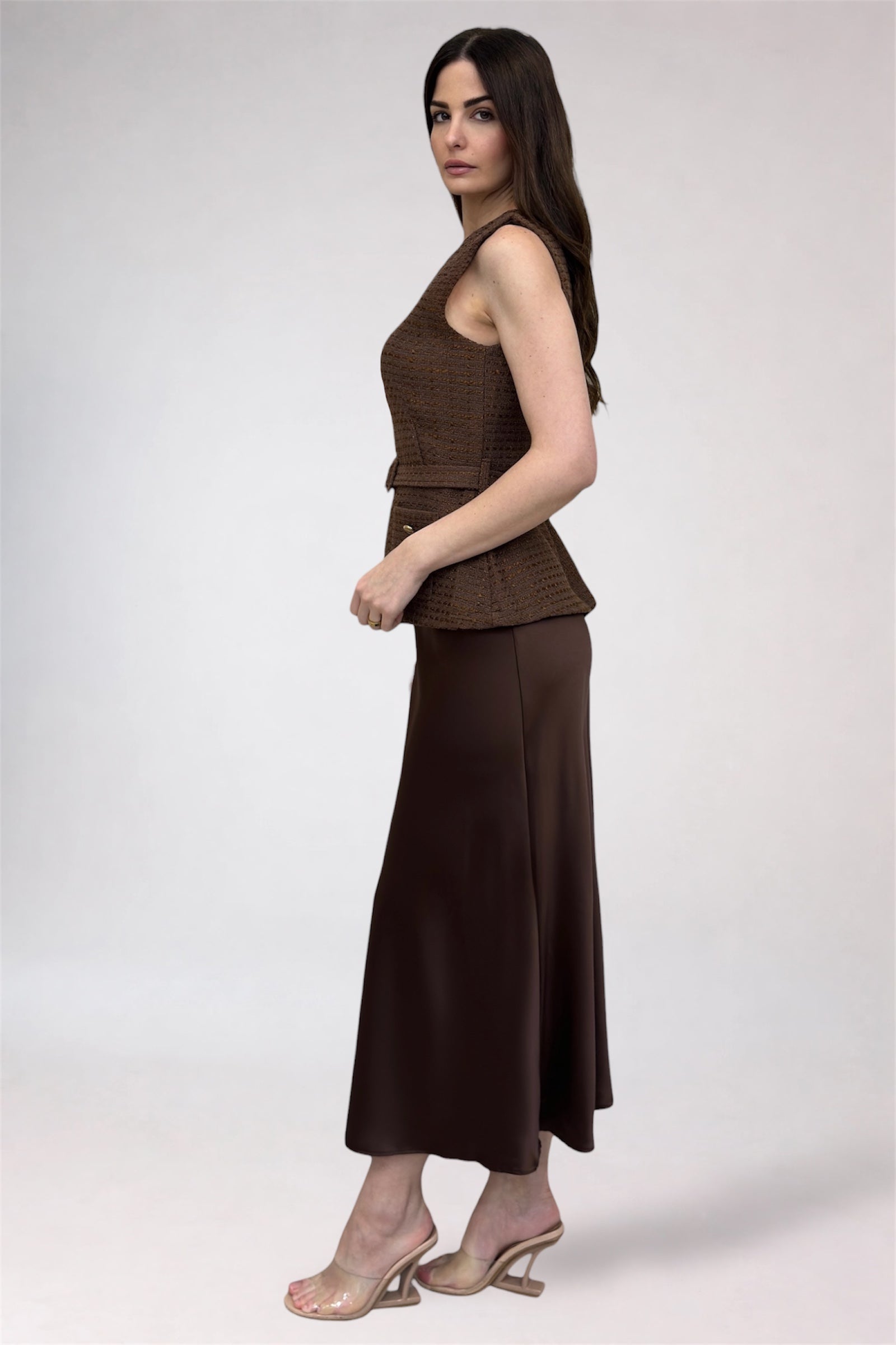 Woman wearing a brown sleeveless top and skirt on a white background