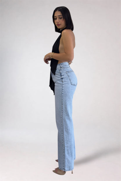 Woman wearing light blue jeans and a black top on a white background