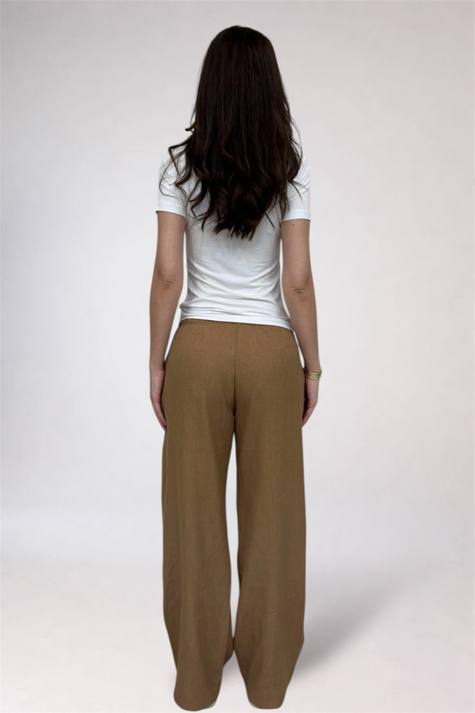 Person wearing a white shirt and brown pants on a plain background
