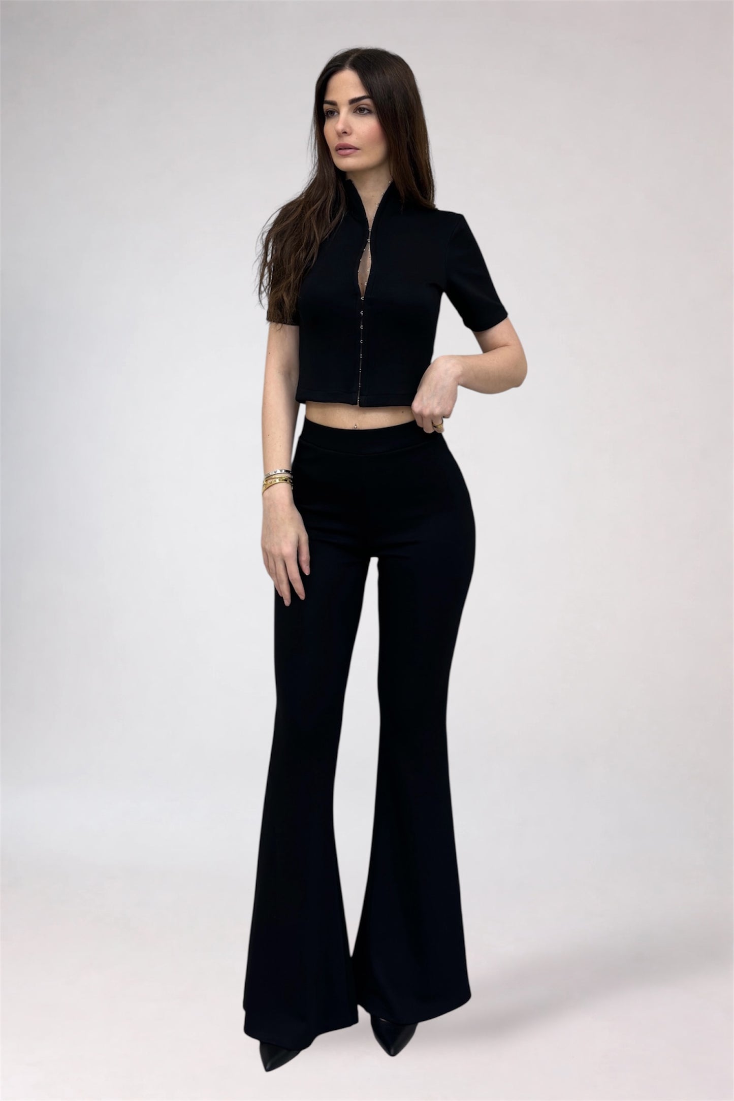 Woman wearing a black outfit with a top and flared pants on a white background