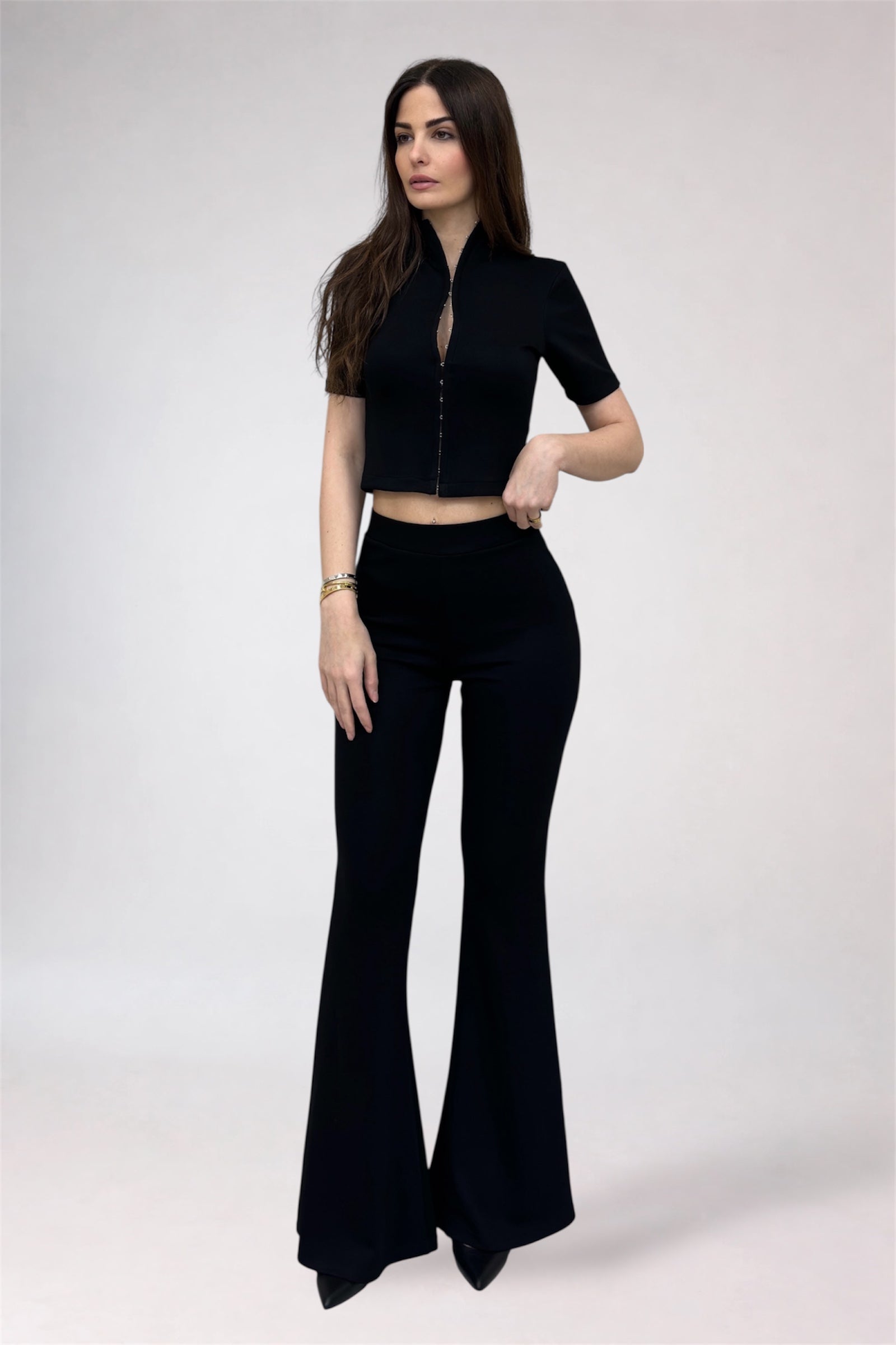 Woman wearing a black outfit with a top and flared pants on a white background