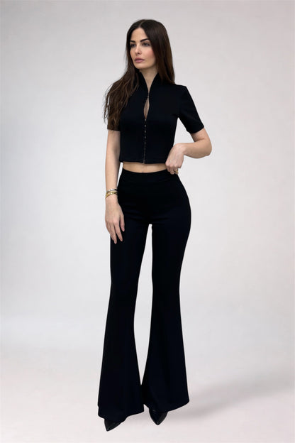 Woman wearing a black outfit with a top and flared pants on a white background