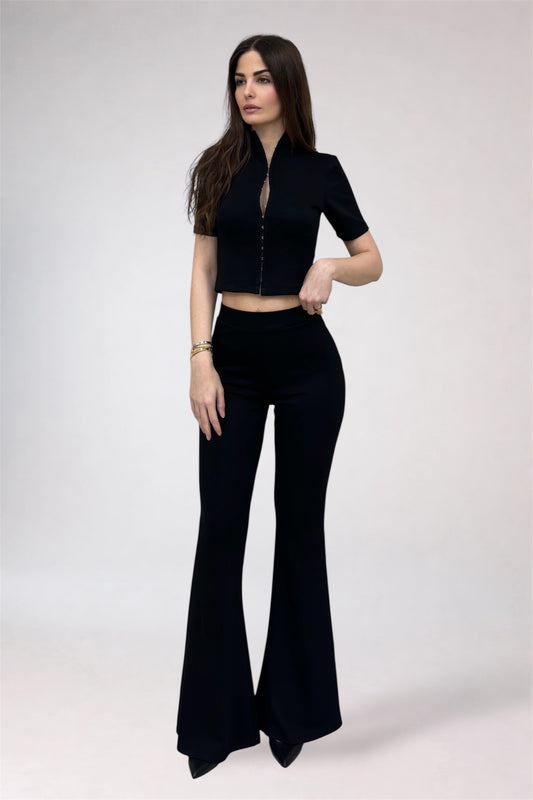Woman wearing a black outfit with a top and flared pants on a white background