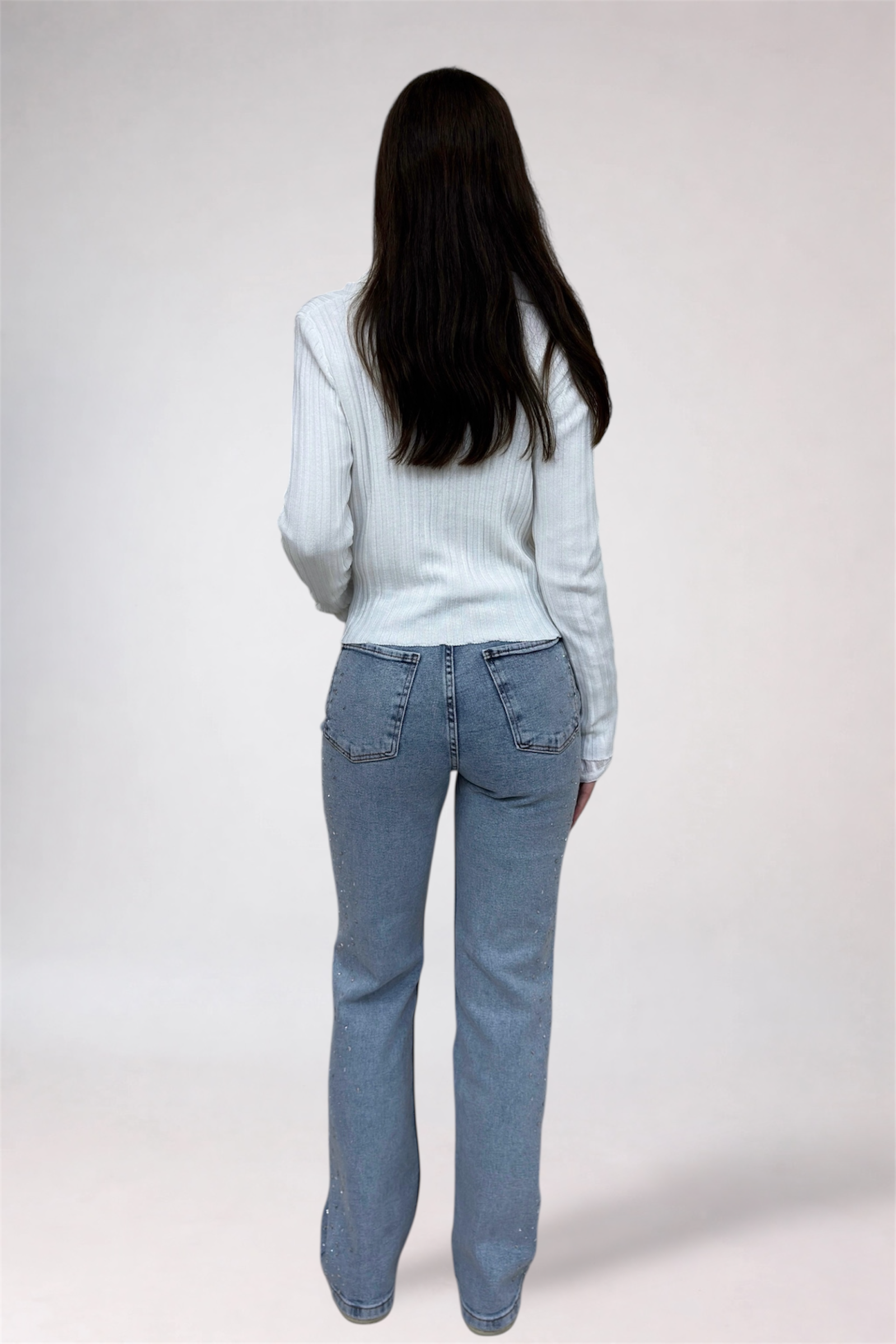 Person wearing light blue jeans and a light gray sweater on a white background