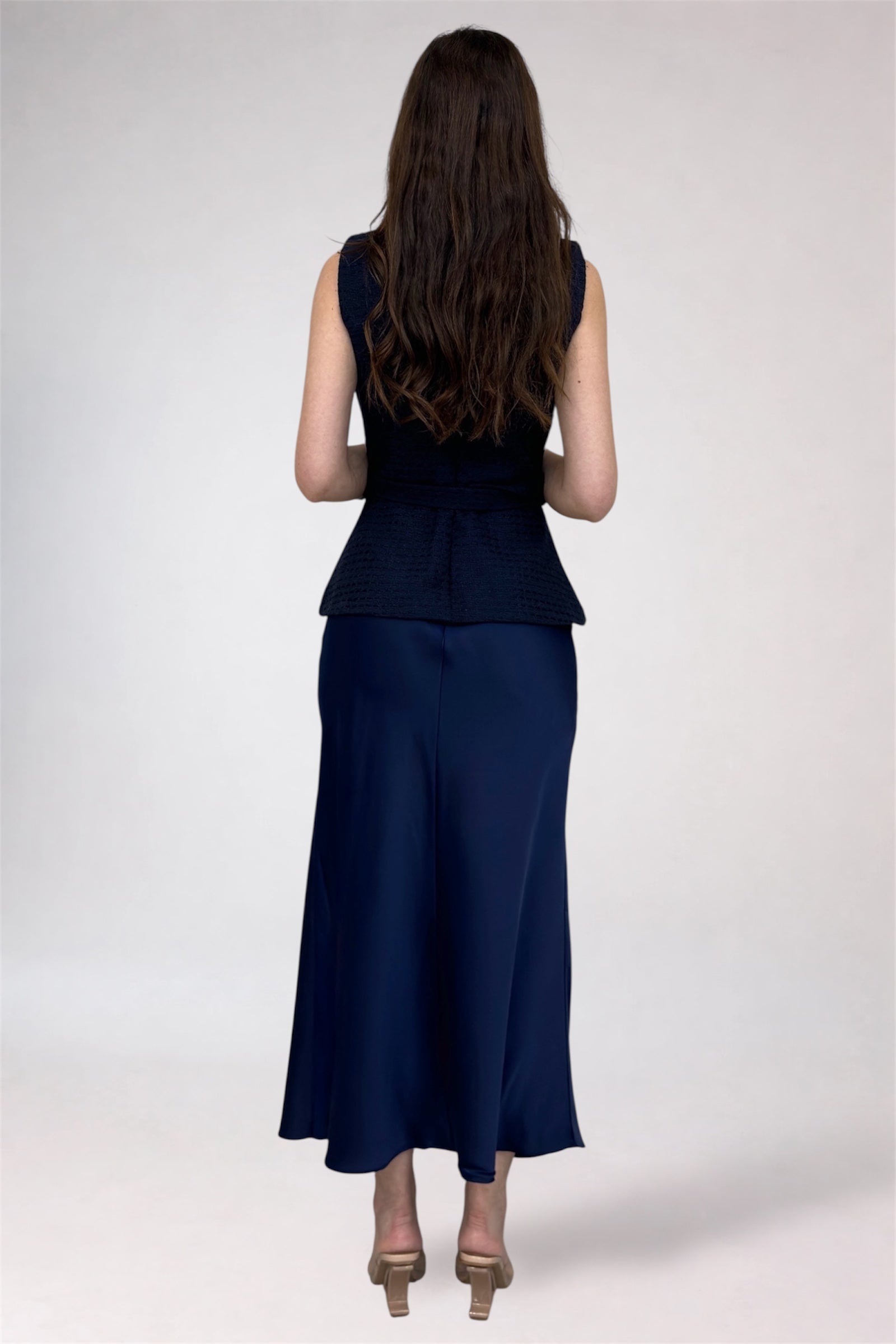 Woman wearing a navy blue sleeveless top and skirt set on a white background