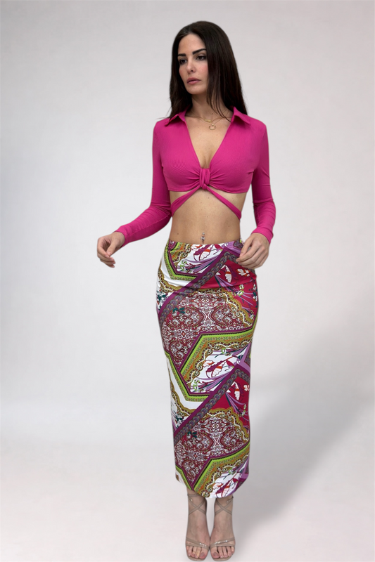 Woman wearing a bright pink top and patterned skirt on a white background