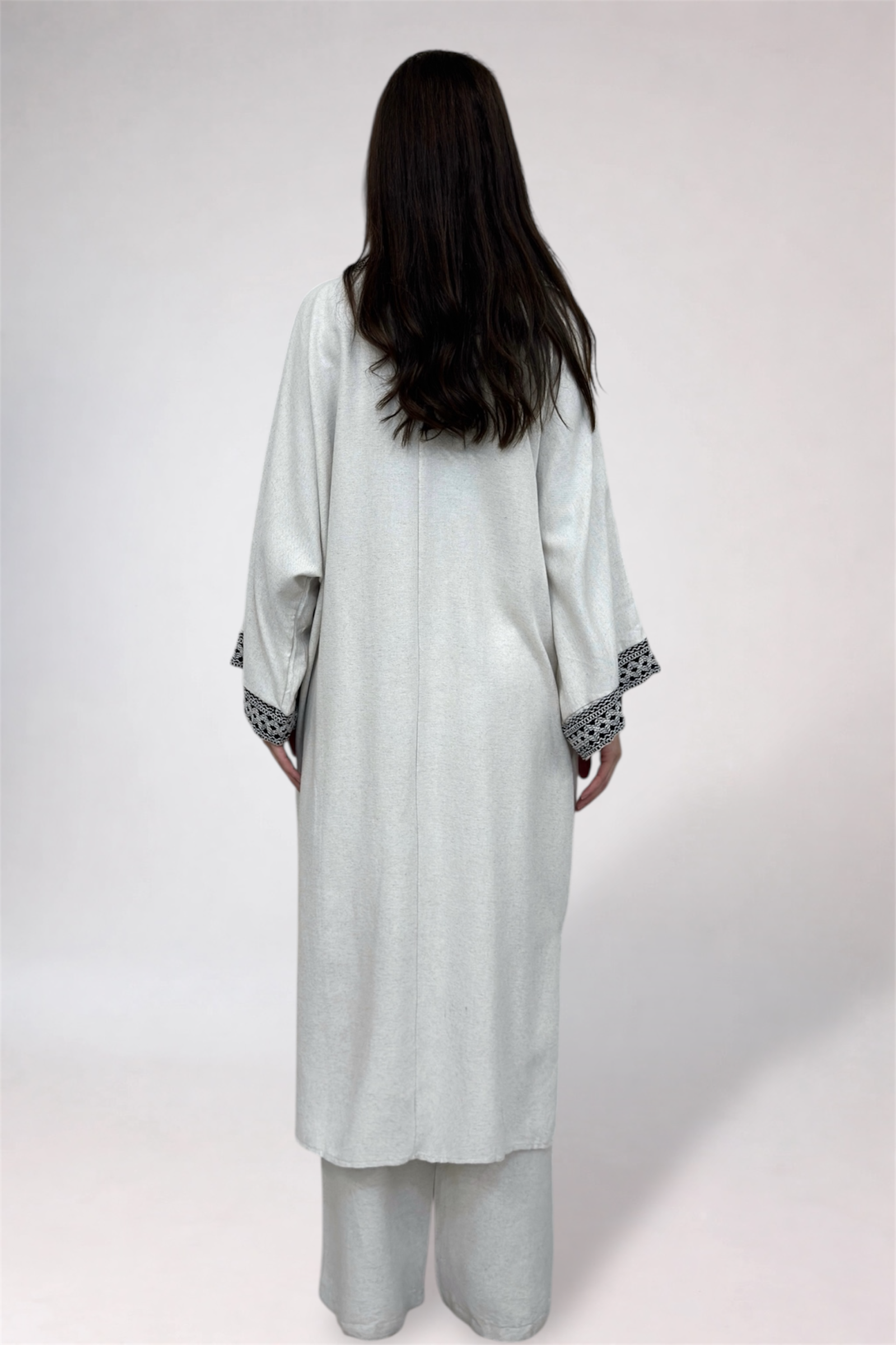 Person wearing a light gray traditional outfit with a white background