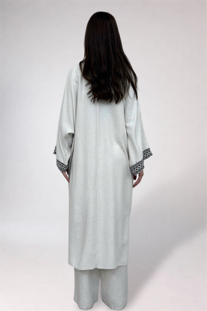 Person wearing a light gray traditional outfit with a white background