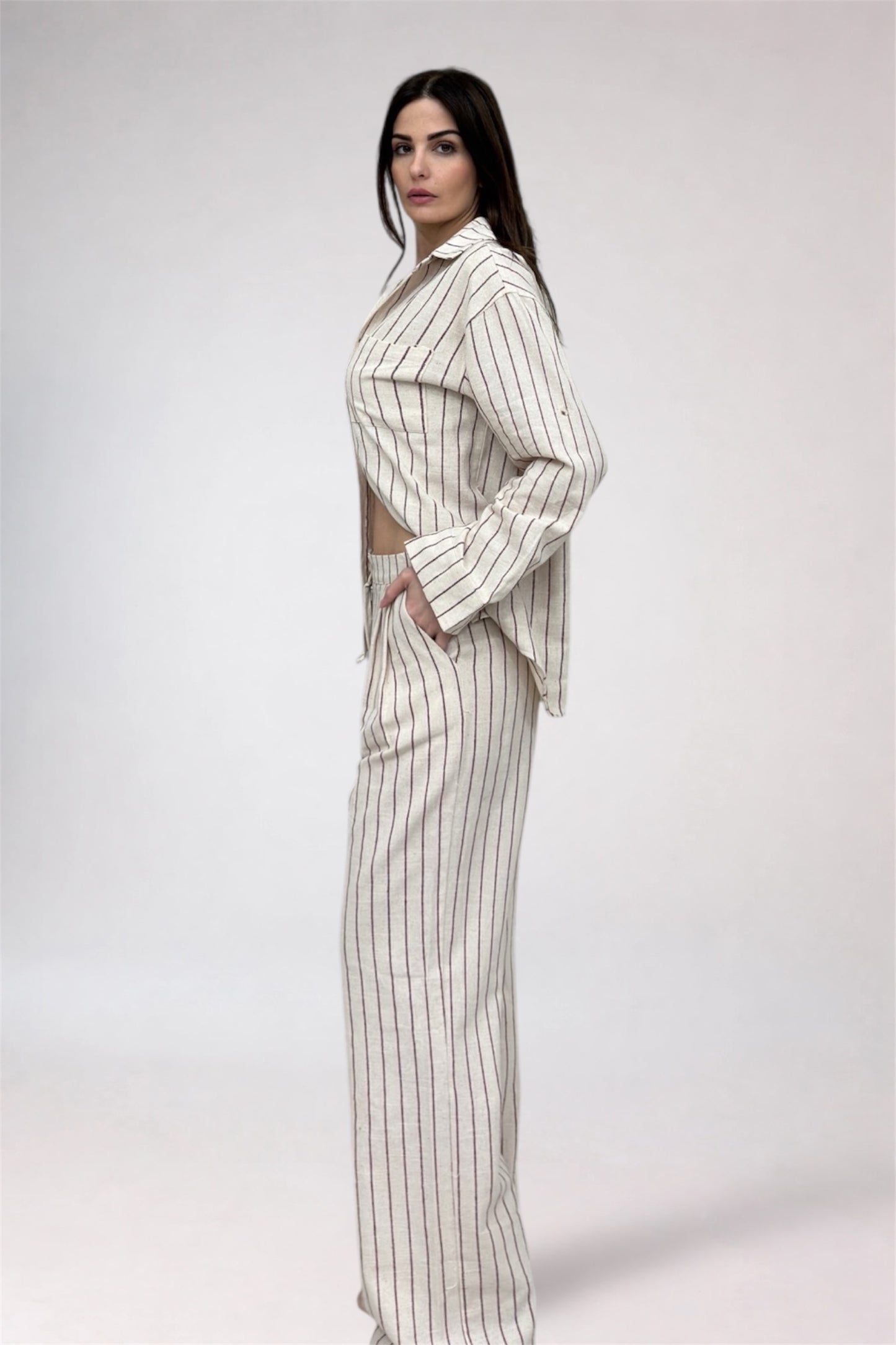 Woman wearing a white and gray striped outfit on a plain background