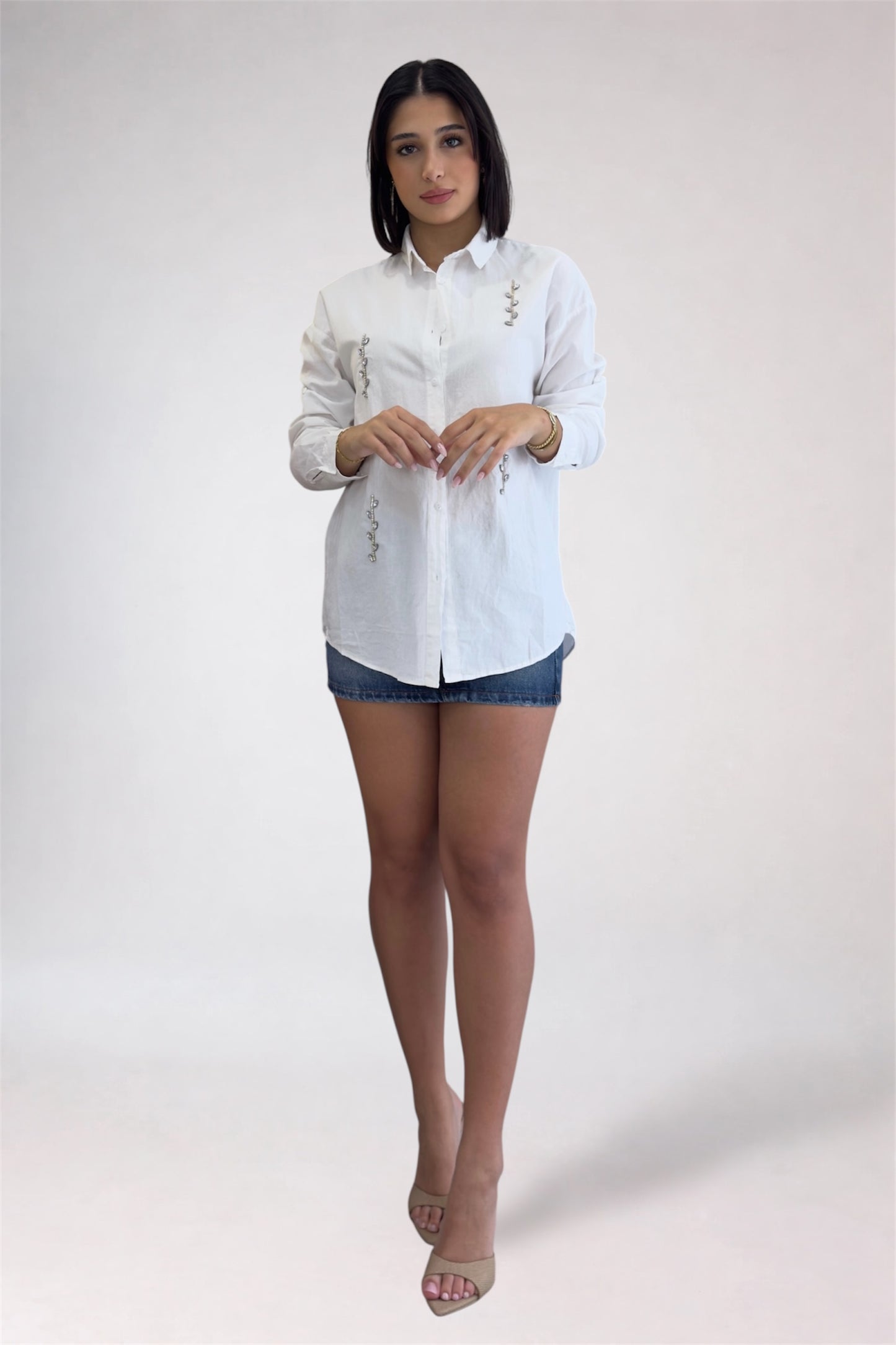 Woman wearing a white button-up shirt and denim shorts on a white background