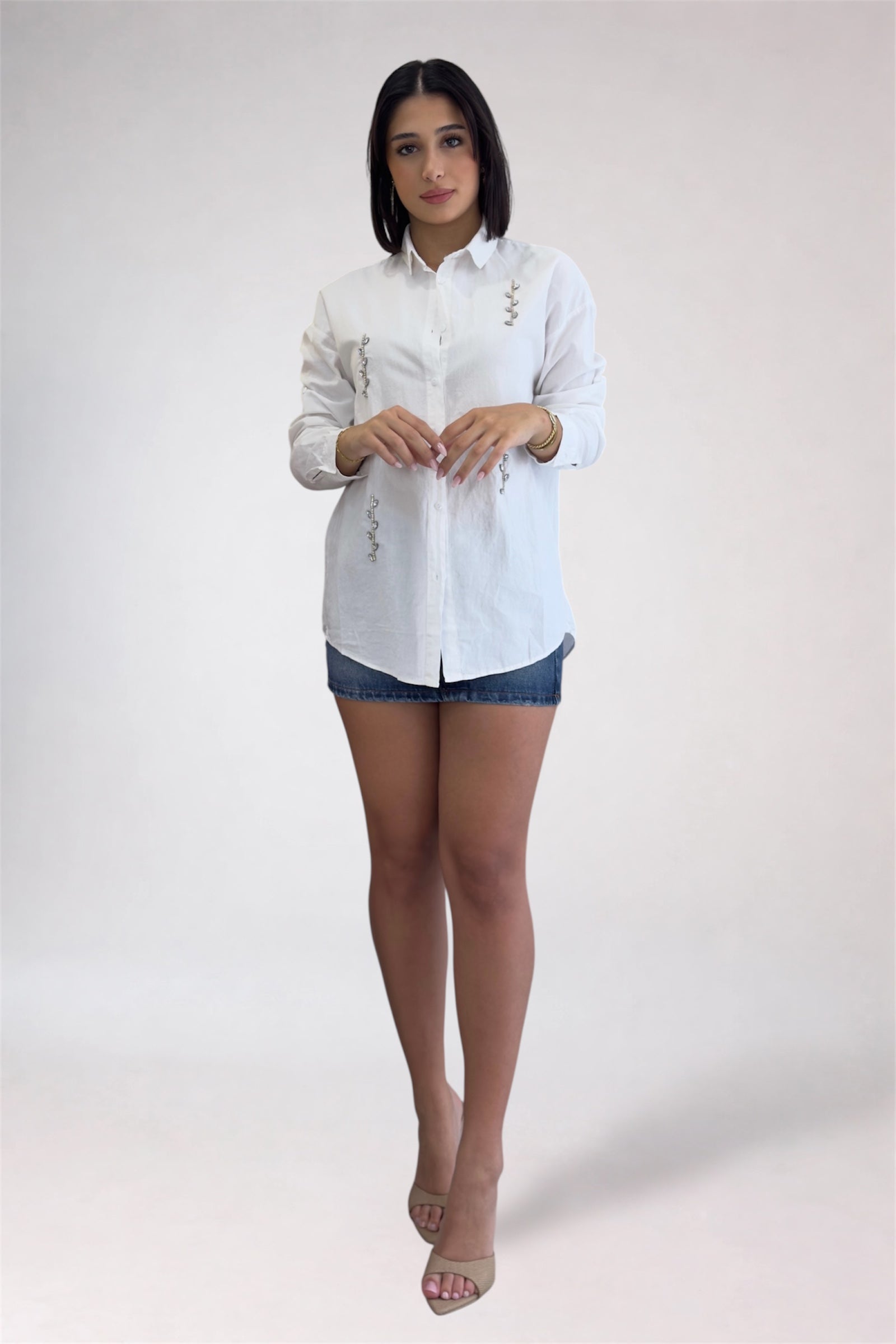 Woman wearing a white button-up shirt and denim shorts on a white background