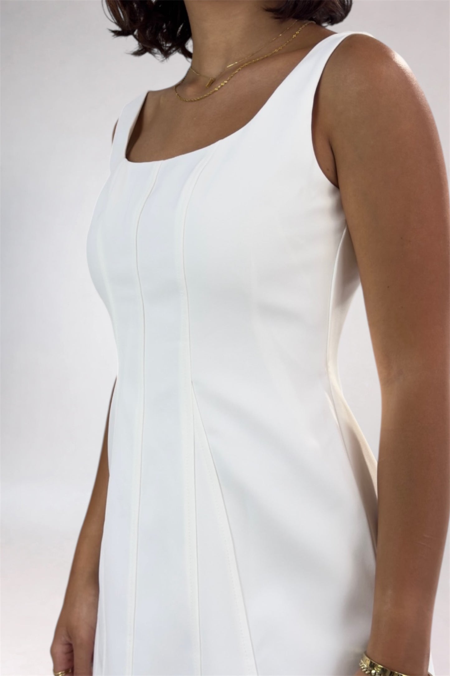 White sleeveless dress worn by a person on a plain background
