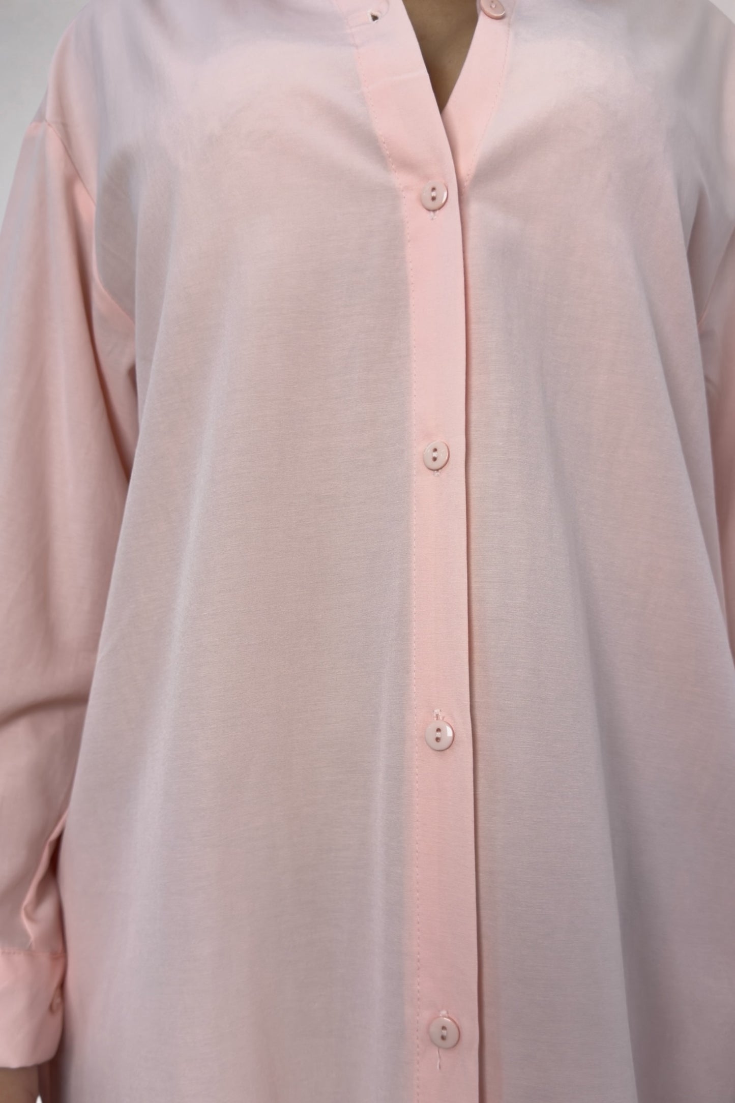 Close-up of a light pink button-up shirt with a plain background
