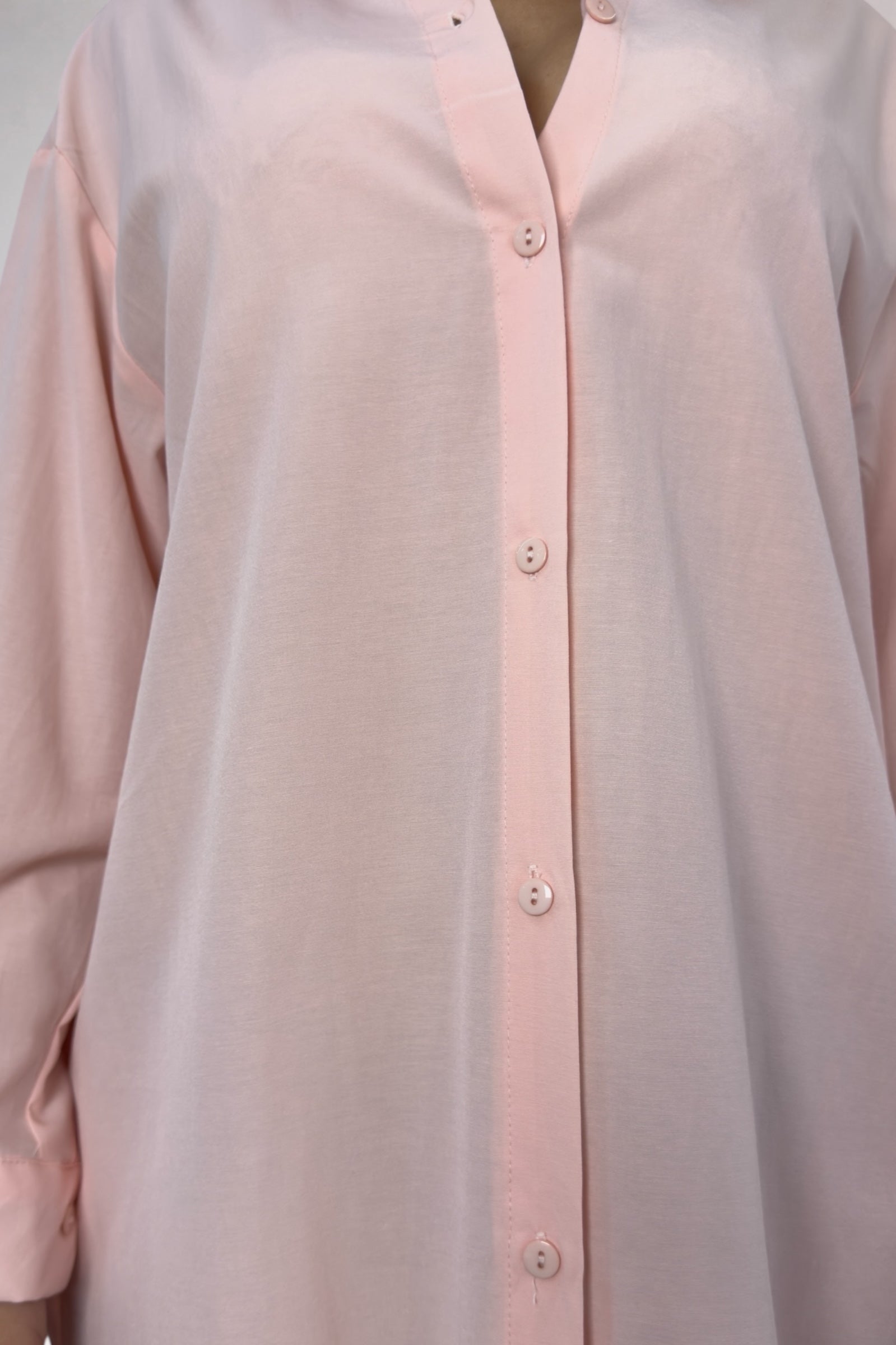 Close-up of a light pink button-up shirt with a plain background