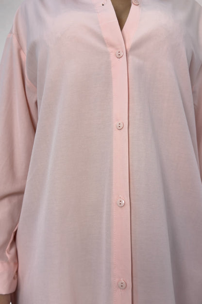 Close-up of a light pink button-up shirt with a plain background