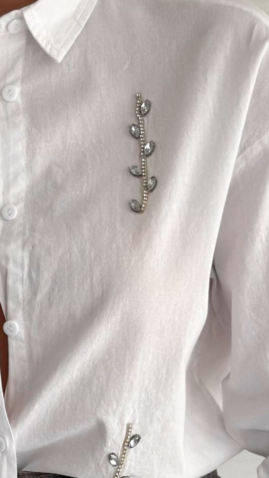 White shirt with a decorative brooch on a white background