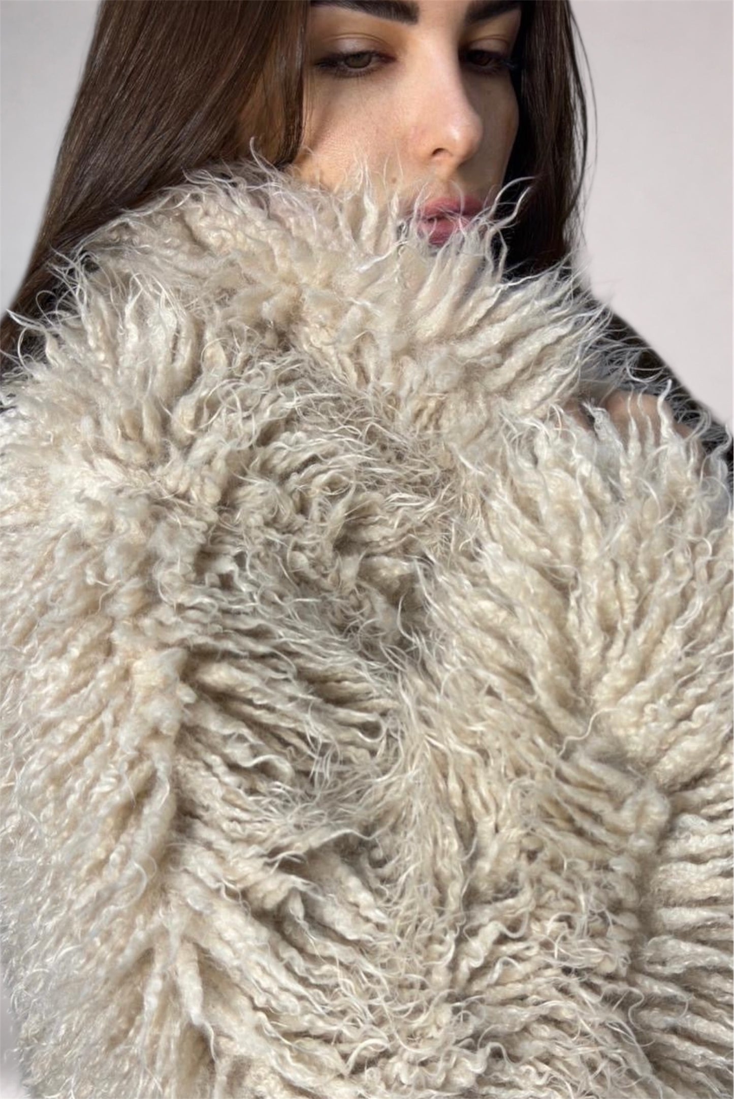 Close-up of a textured beige fabric with a person wearing it.