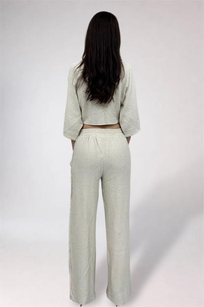 Person wearing a light-colored outfit with wide-leg pants on a white background